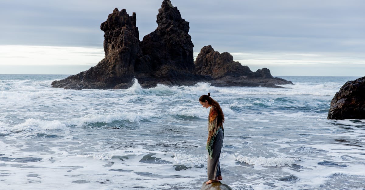 Arriving in Venice - Single American Woman - Side view of lonely sad female standing on stone in front of storming ocean