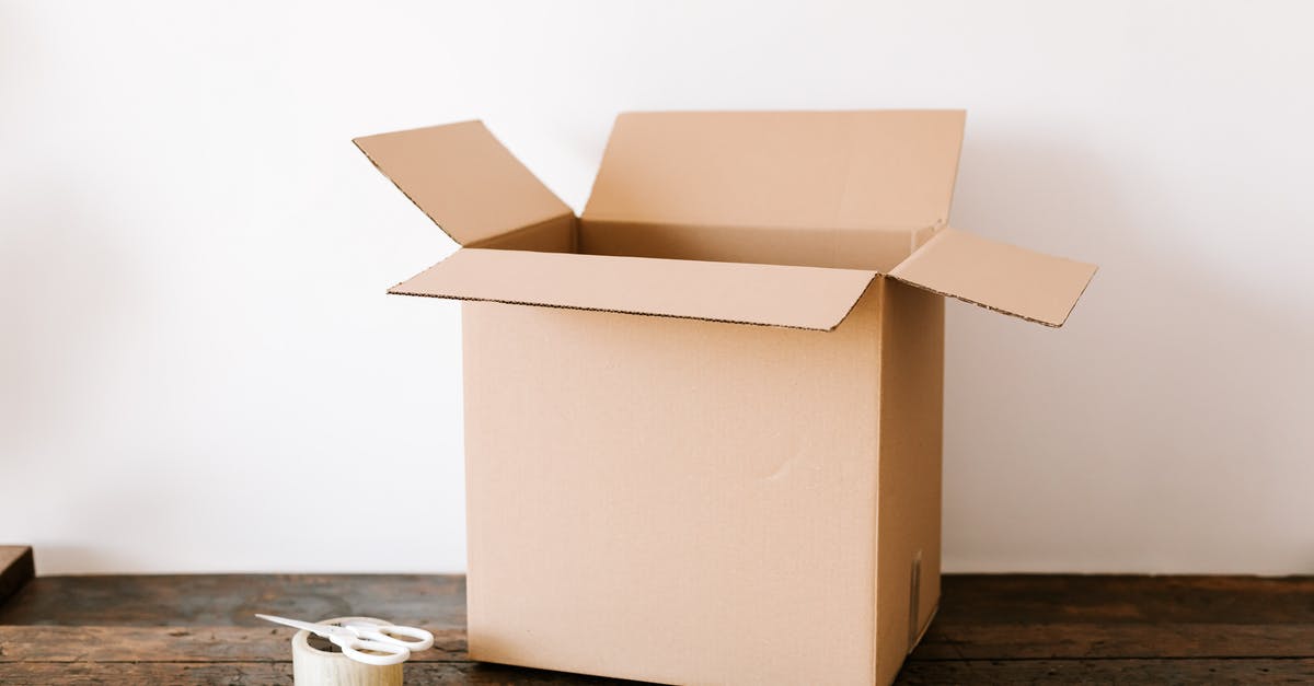 At JFK, can you move between terminals airside on domestic flights? - Opened cardboard container placed on old wooden desk near tape and scissors before relocation against white wall