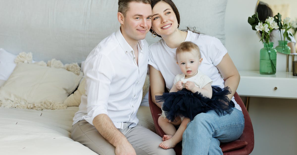 At what age an infant can start flying? - Photo of Couple with a Baby Sitting.