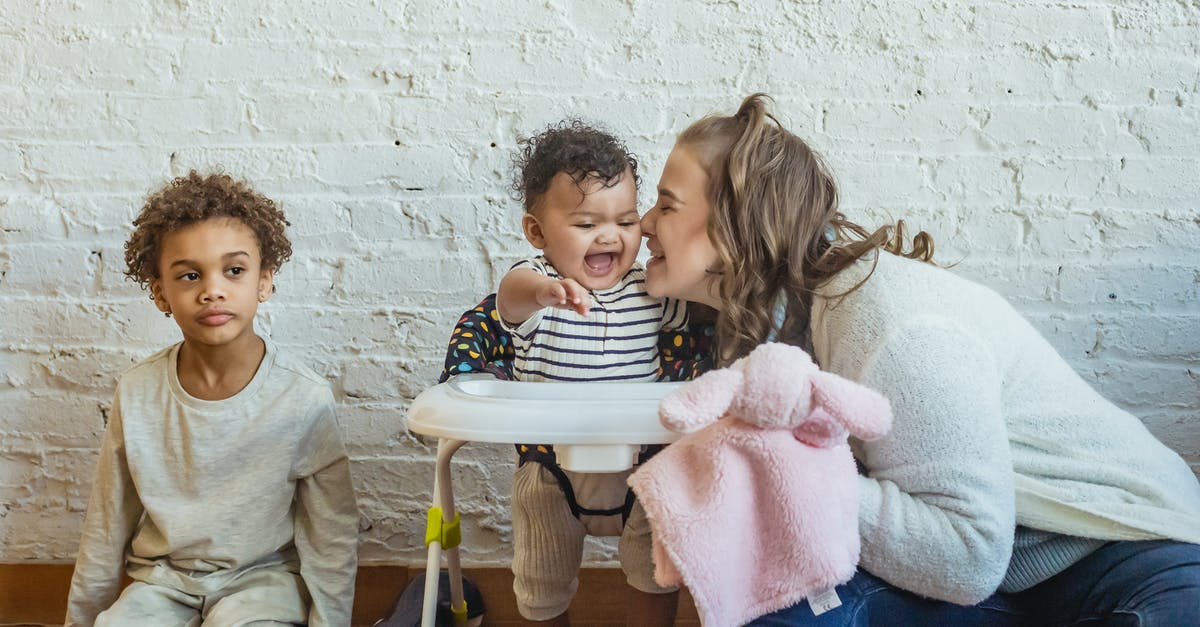 At what age an infant can start flying? - Happy mother sitting and playing with children