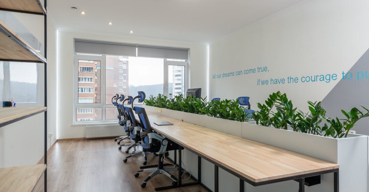 Australian visa for conference - invitation letter - Armchairs at table with green plants in stylish conference room with motivational inscription on wall and window in business center