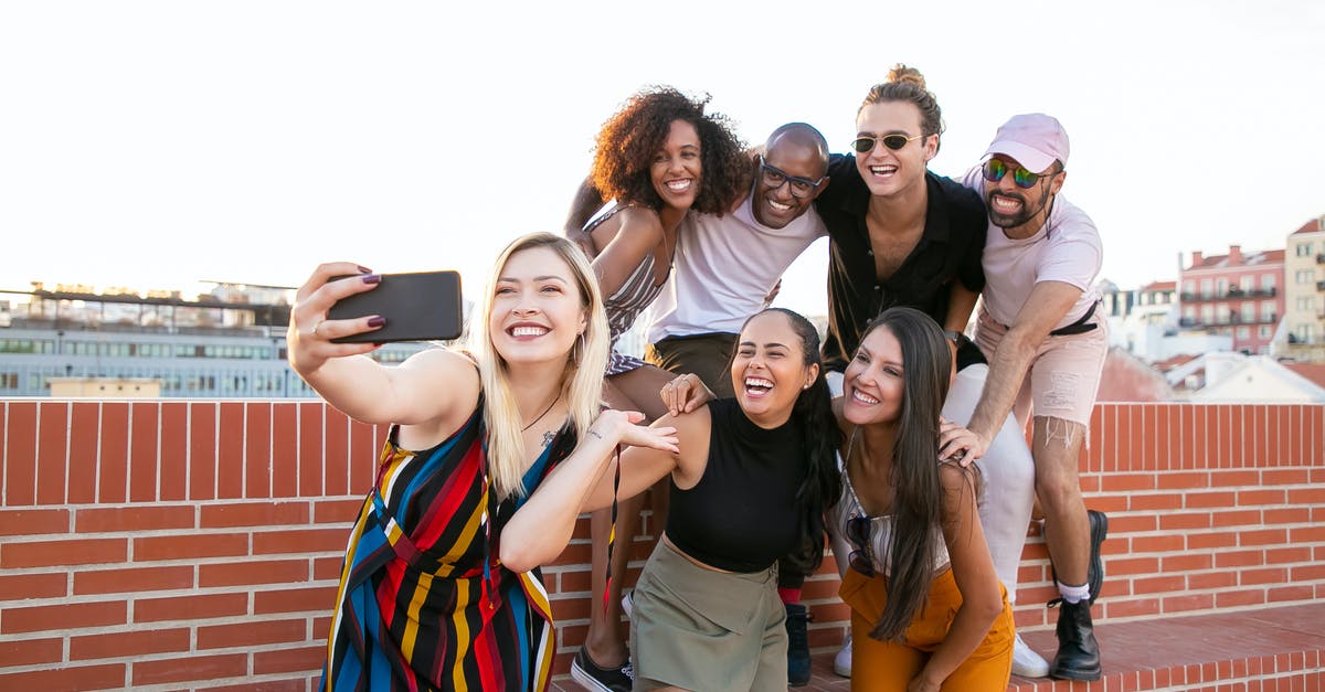 Austria - Czech Republic - Germany - What is the best option for mobile phone - Group of cheerful young male and female multiracial friends laughing and taking selfie on smartphone while spending time together on terrace