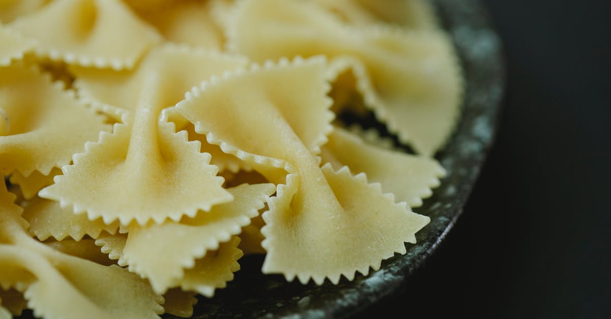 Authentic (non-touristic) places, where Italians eat, in Verona and Venezia [closed] - High angle of raw dried traditional Italian farfalle pasta in bowl on black background