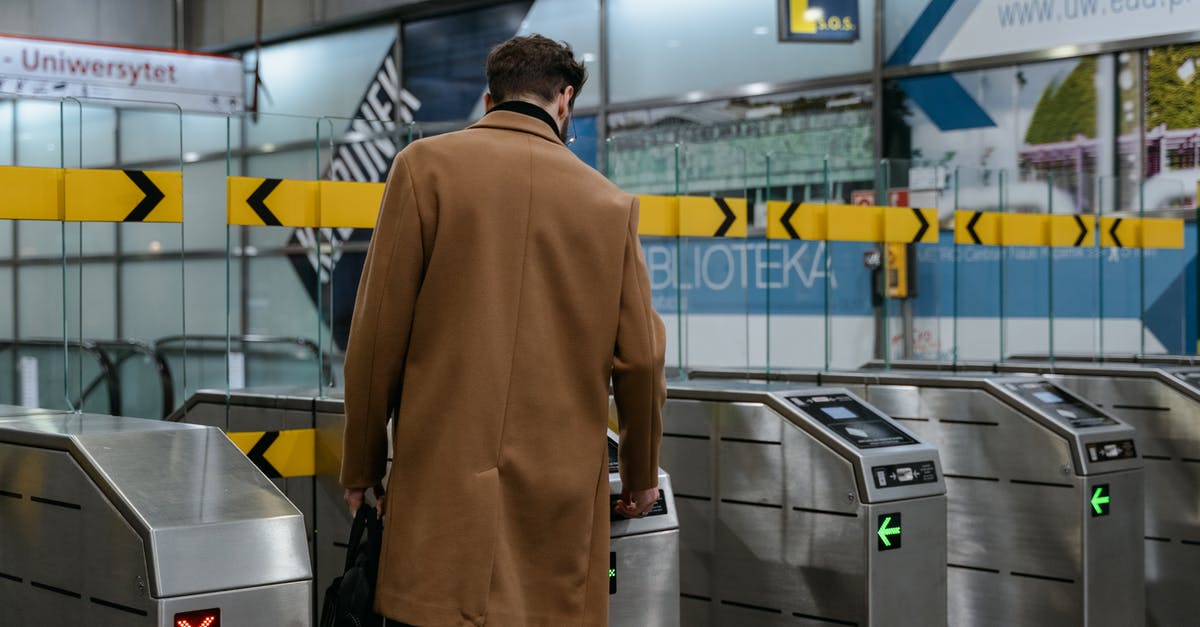 Automatic Visa Re validation (US) - A Person in Brown Coat Entering a Subway Automated Ticket Barrier