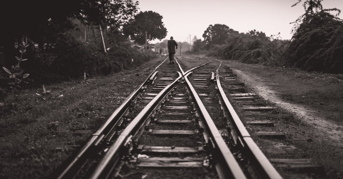 Avoid long walking when changing between Tokyo subway lines - Grayscale Photo of a Person Walking on Railway Track 