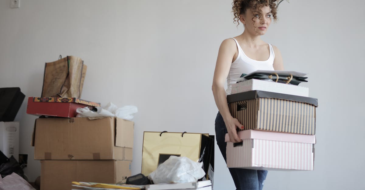 Avoiding important carry-on luggage being taken away - Concentrated woman carrying stack of cardboard boxes for relocation