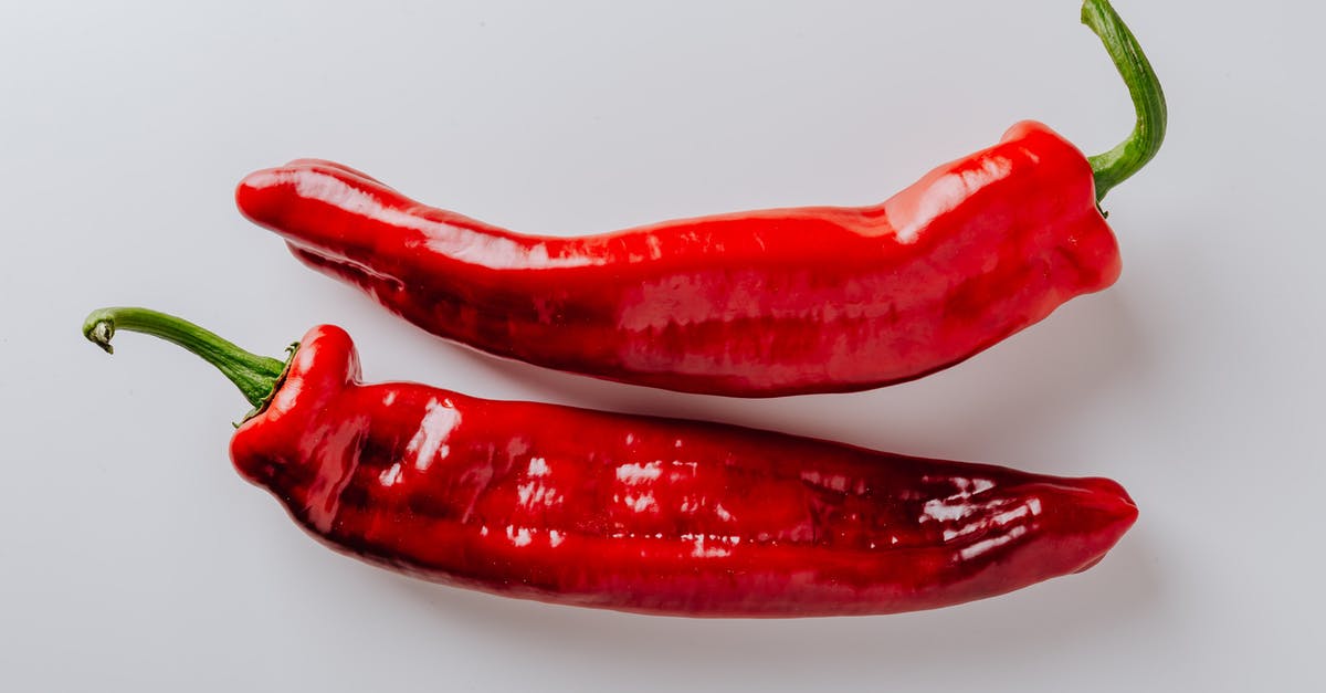 Avoiding spicy food while touring South Korea - From above of pair of hot chili peppers with green sprouts and smooth surface put on white table