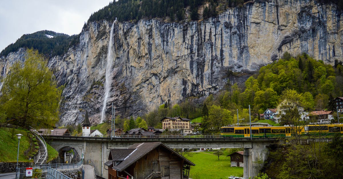 Avoiding tilting trains in Switzerland - Train riding in mountainous countryside near waterfall flowing through rocky cliff