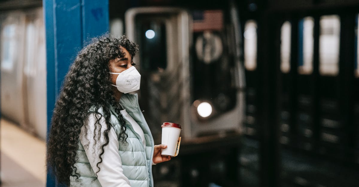 Azerbaijan Transit Visa for Iranian Citizens - Calm African American female in casual outfit and protective mask standing on underground platform near arriving train