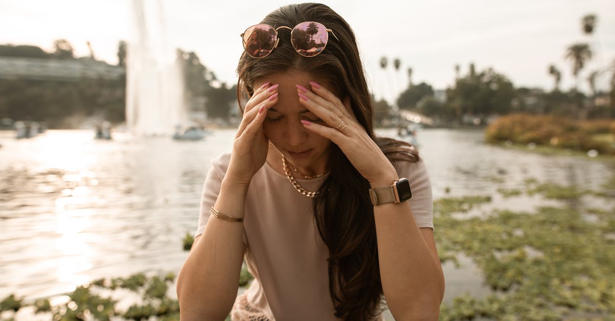 B2 VISA REJECTION DILEMMA [closed] - Distressed woman sitting on lakeside and touching face in despair