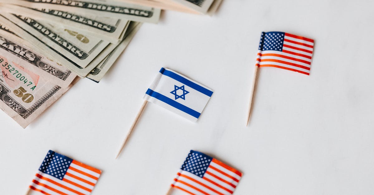 Baby with passport from different country than his parents - From above closeup of Israeli and American flags on toothpicks and different nominal pars of dollar banknotes on white background