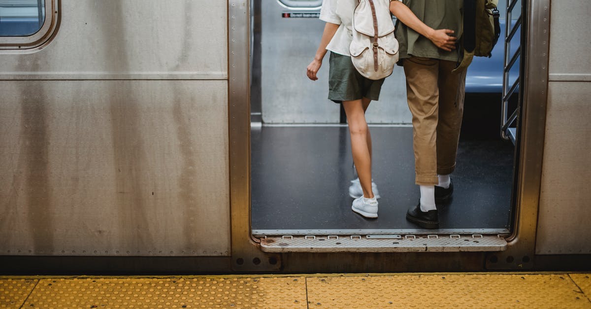 Backpack trip to Europe [closed] - Back view of crop anonymous young couple in stylish outfits hugging while entering wagon of subway train