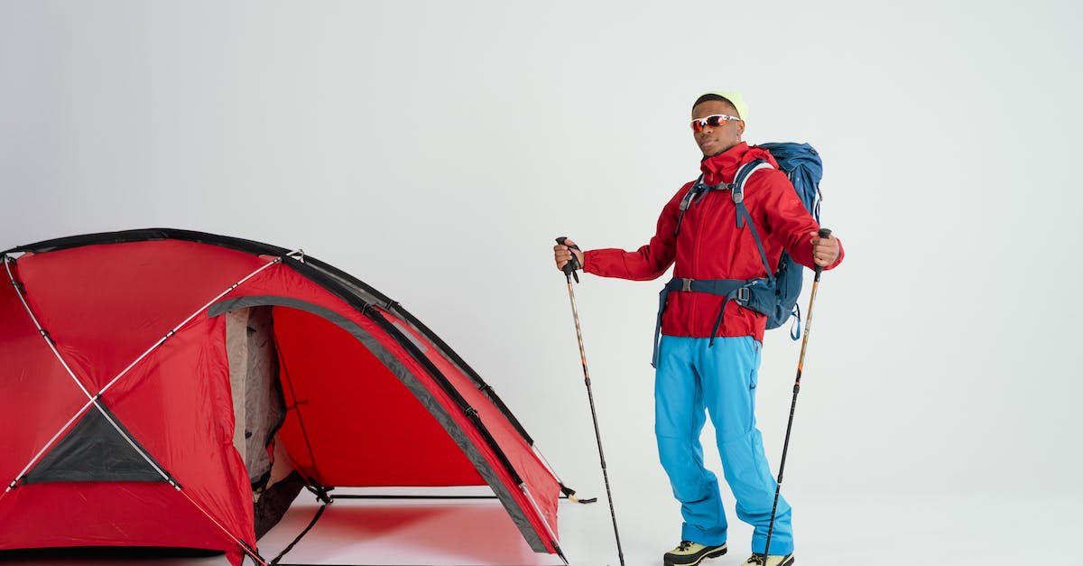 Backpacking - travelling with 'smart' clothes - Man in Red Jacket and Black Pants Holding Red and White Tent