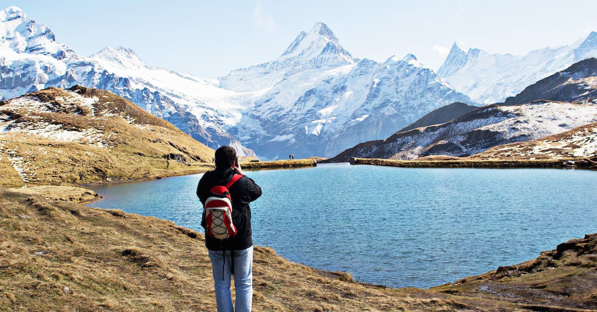 Backpacking in Europe for the first time [closed] - Standing Man Wearing White and Red Backpack in Front of Calm Body of Water