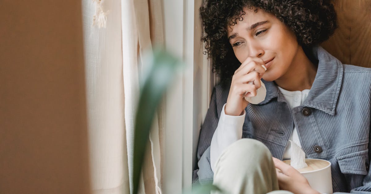 Bad hostel, recourse? - Sad African American female with tissue sitting on windowsill and crying while suffering from sorrow