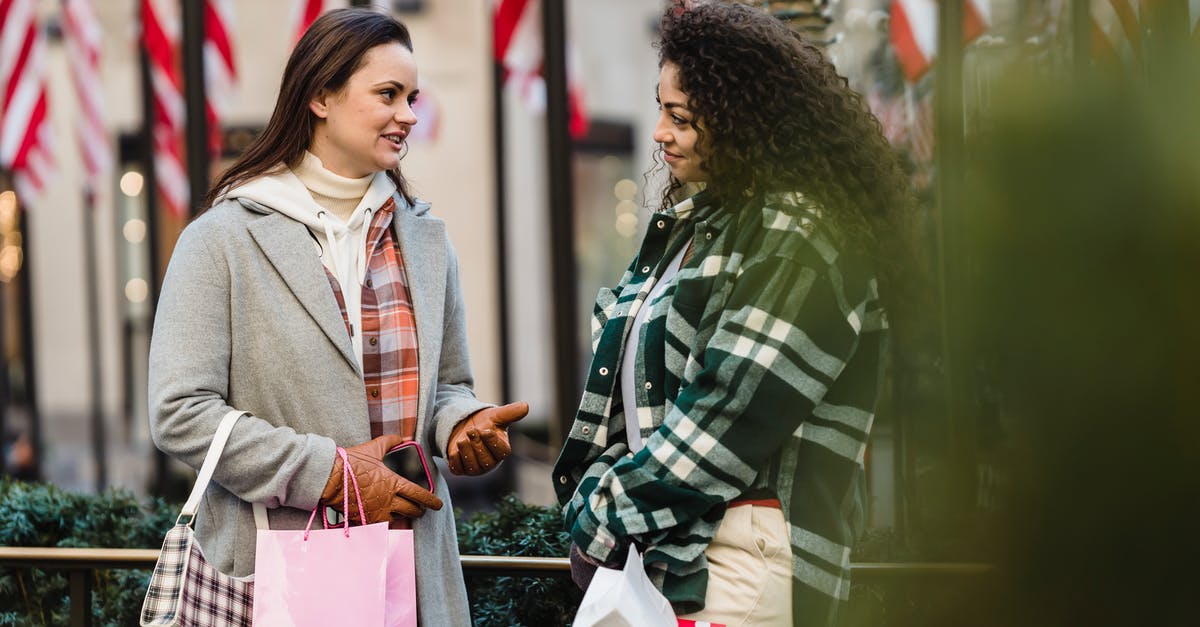 Bag wrapping at airports in USA - Positive young multiracial women chatting on street after shopping