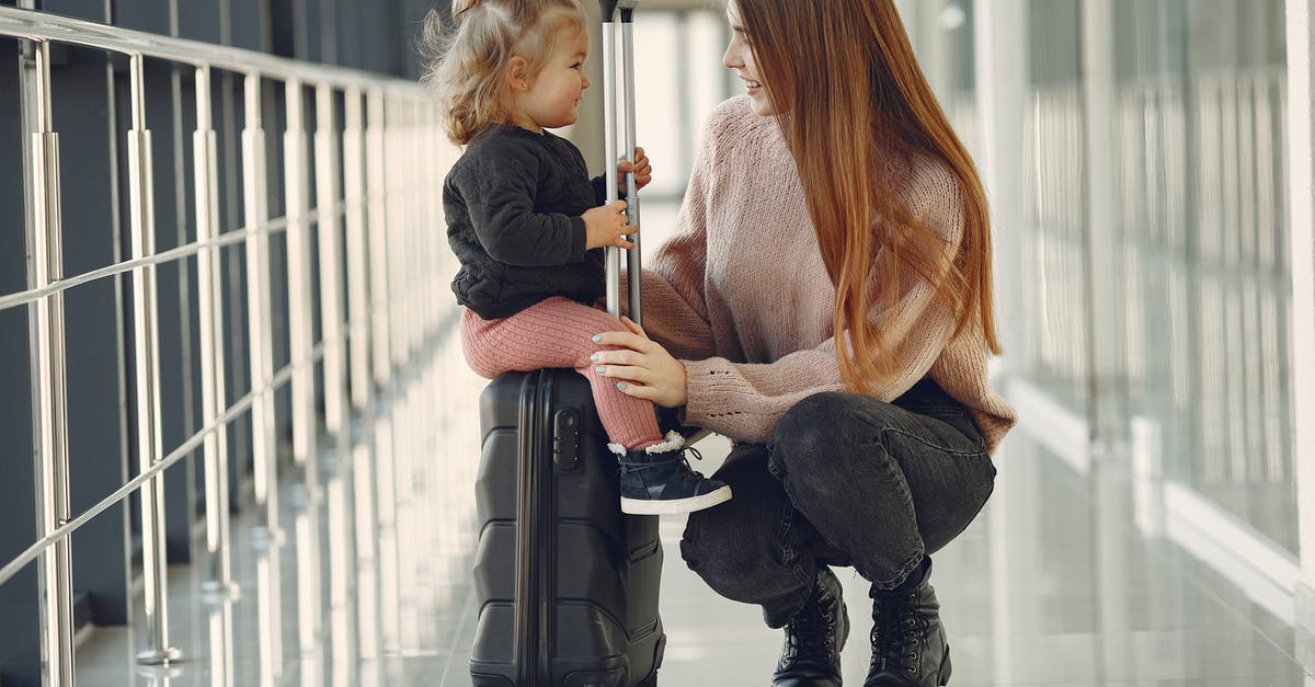 Baggage allowance of separate domestic flights with a connecting international flight? - Full length of positive content woman and cute stylish blond little girl sitting on black suitcase in airport corridor while waiting for flight