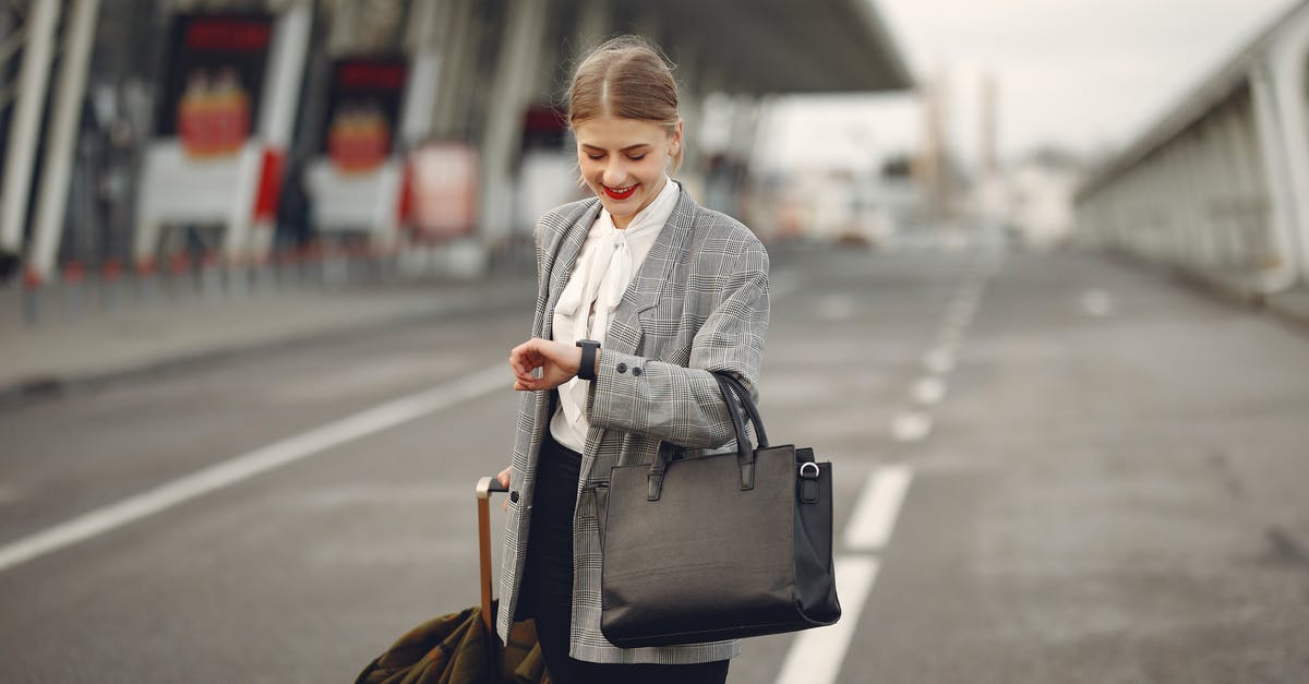 Baggage checked? - Positive young businesswoman with suitcase hurrying on flight on urban background