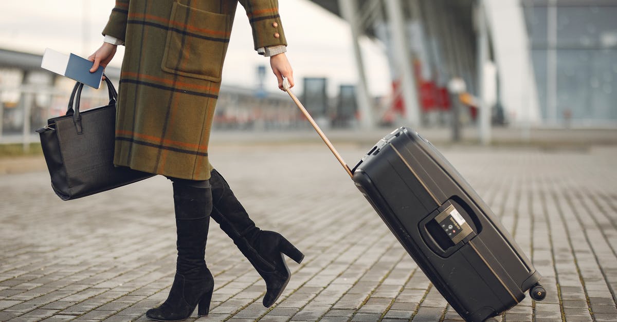 Baggage issues on Qatar Airways ticket - Stylish woman with suitcase and bag walking on street near modern airport terminal