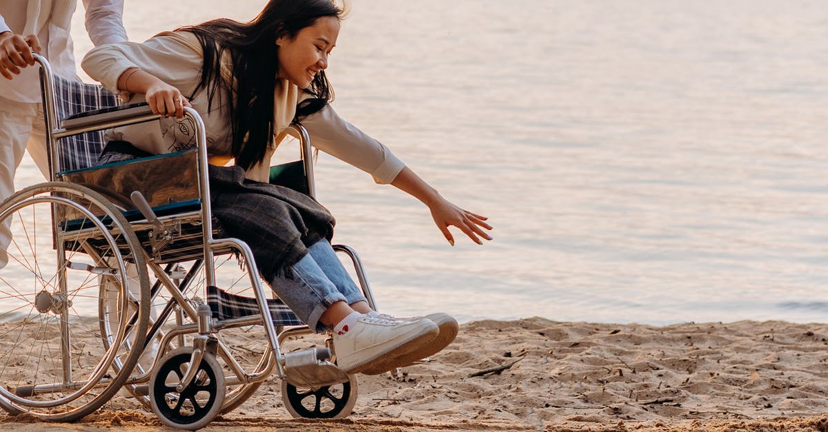 bags and wheelchair - Woman in Black Tank Top Sitting on Blue and Gray Wheelchair on Beach