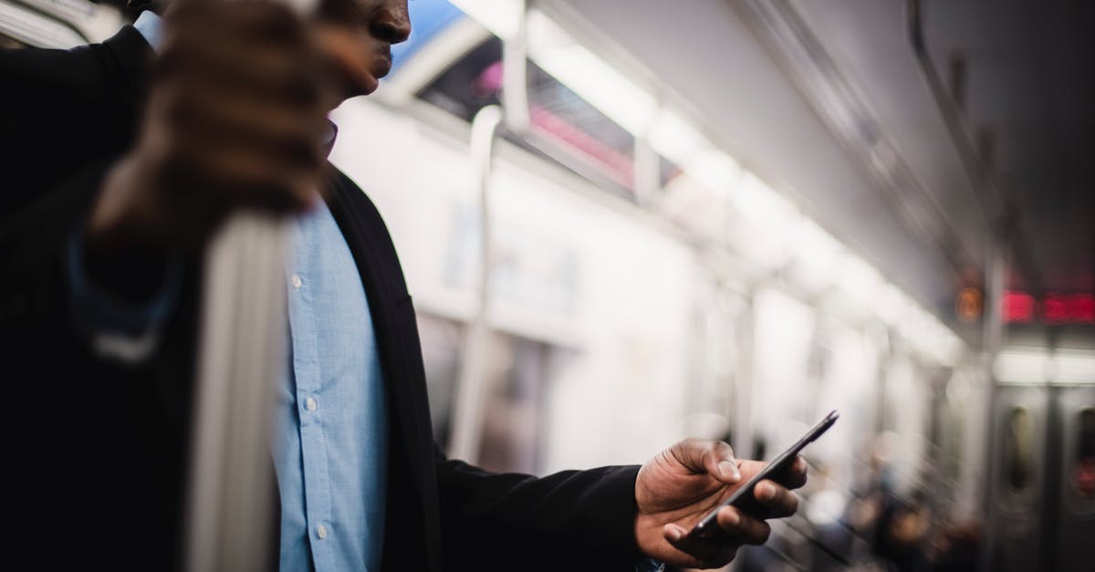 Barbados via JFK - Transit on Media Visa - Black man using mobile while commuting by train