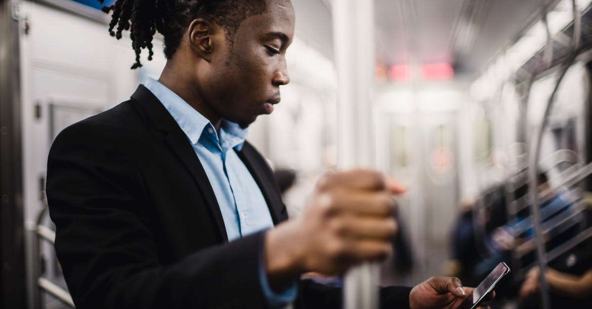 Barbados via JFK - Transit on Media Visa - Young African American man using smartphone on train