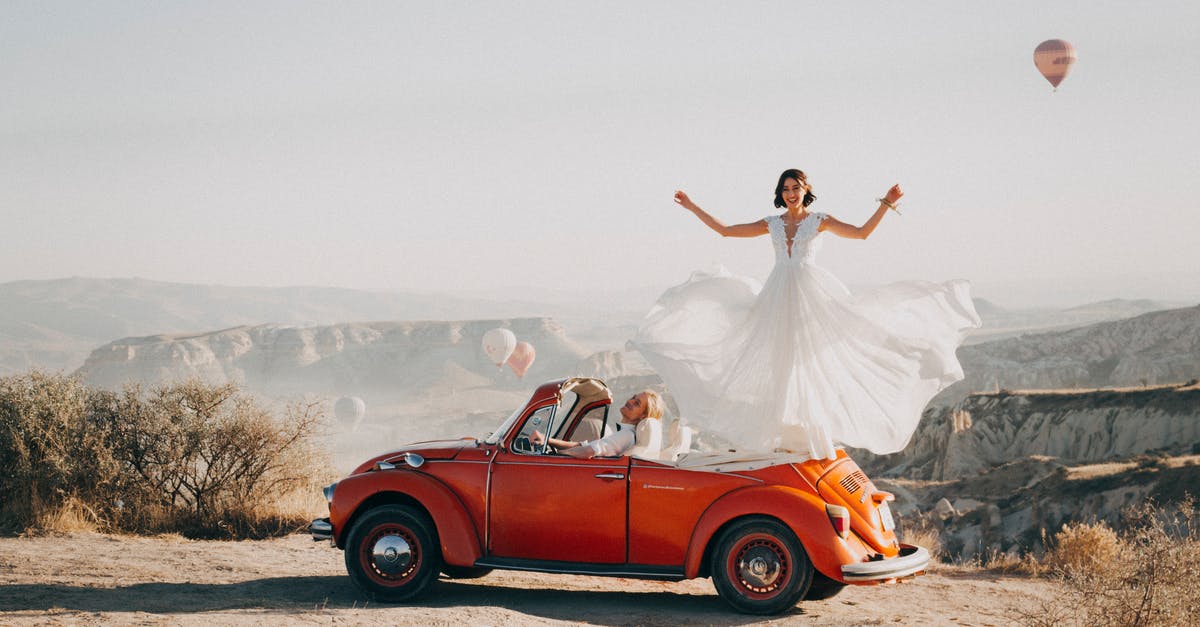 Become a travel agent just for yourself to get deals - Woman Standing on Volkswagen Beetle