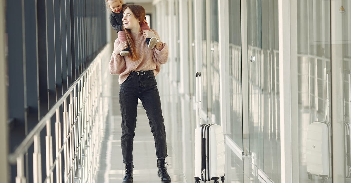 Being separated from one's young children on a flight - Cheerful woman with daughter and suitcase in airport