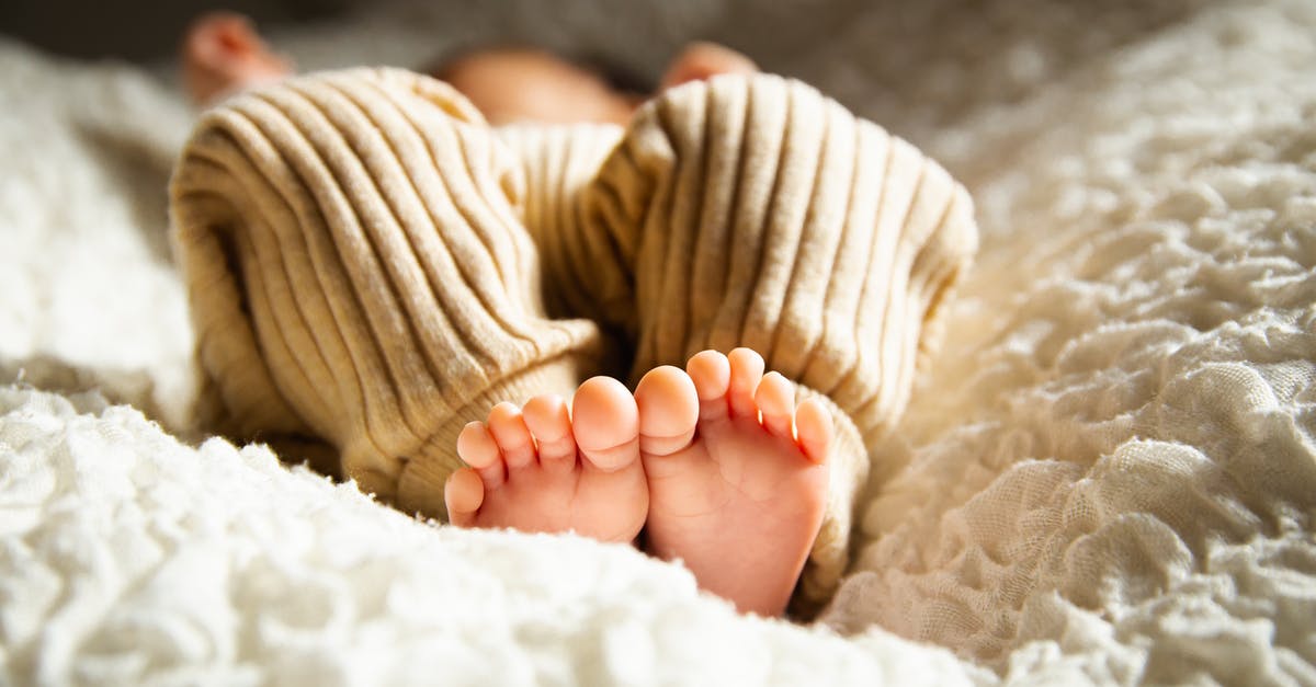 Below standard baby crib - Anonymous barefooted baby sleeping on soft bed in sunlight