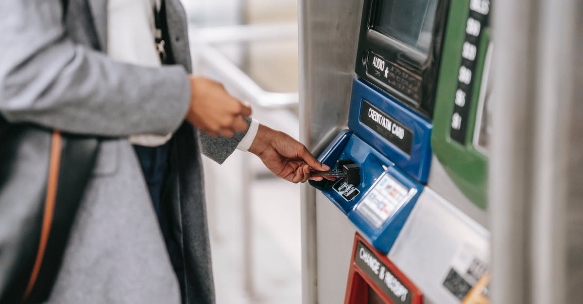 Berlin: Pay per use travel card for public transport - Side view of crop unrecognizable female in stylish clothes using credit card while buying metro ticket via electronic machine