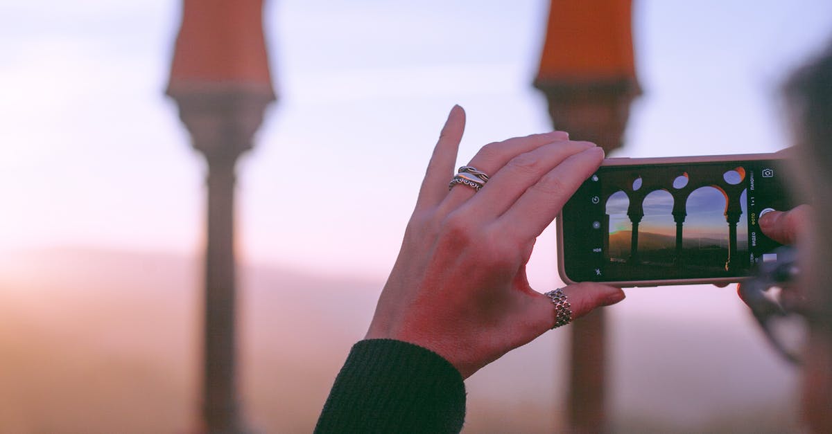 Best phone provider for a three-month visit to Thailand? [duplicate] - Crop unrecognizable female traveler taking photo of old oriental castle with arched passage on mobile phone against sunset sky