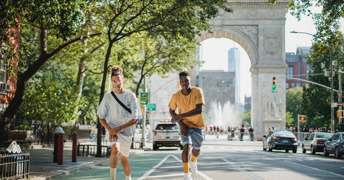 Best practice to apply for US Family/Group Visa - Full body of serious multiethnic male skateboarders riding skateboards along road against Triumphal Arch in New York