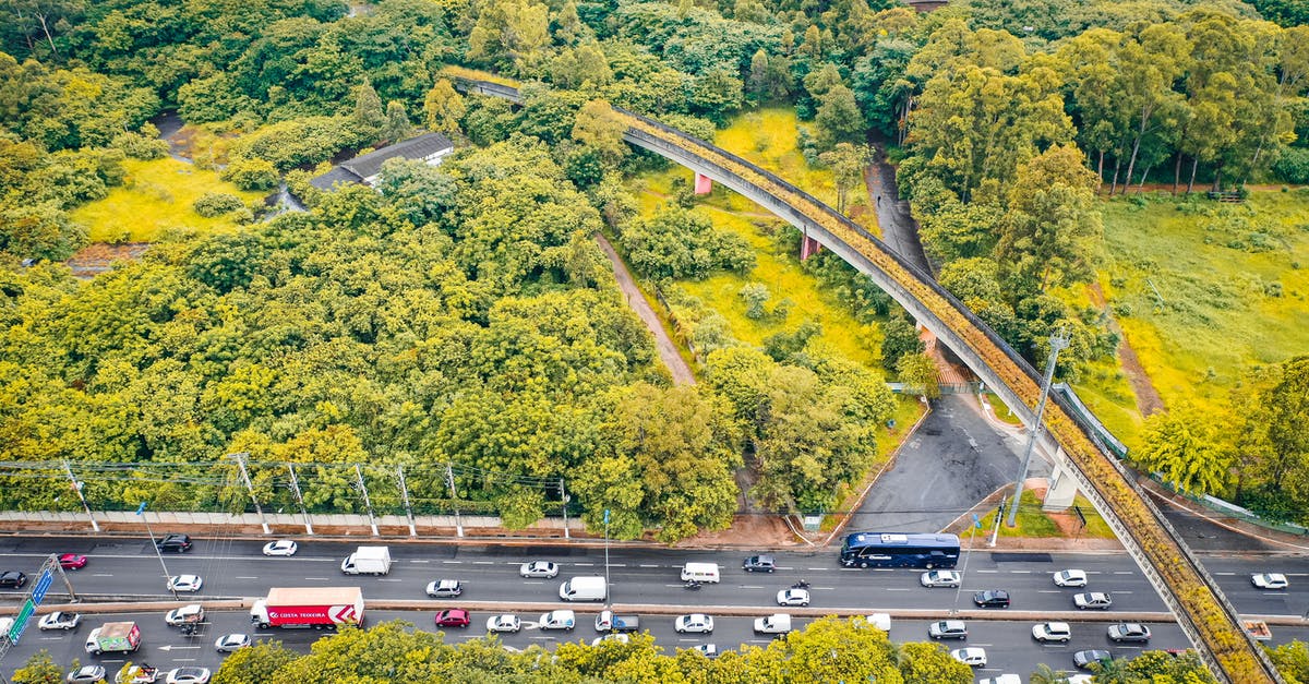 Best Route from Zurich Airport to Rhine Falls - Drone view of urban bridge and roadway with transport between colorful lush woods in fall