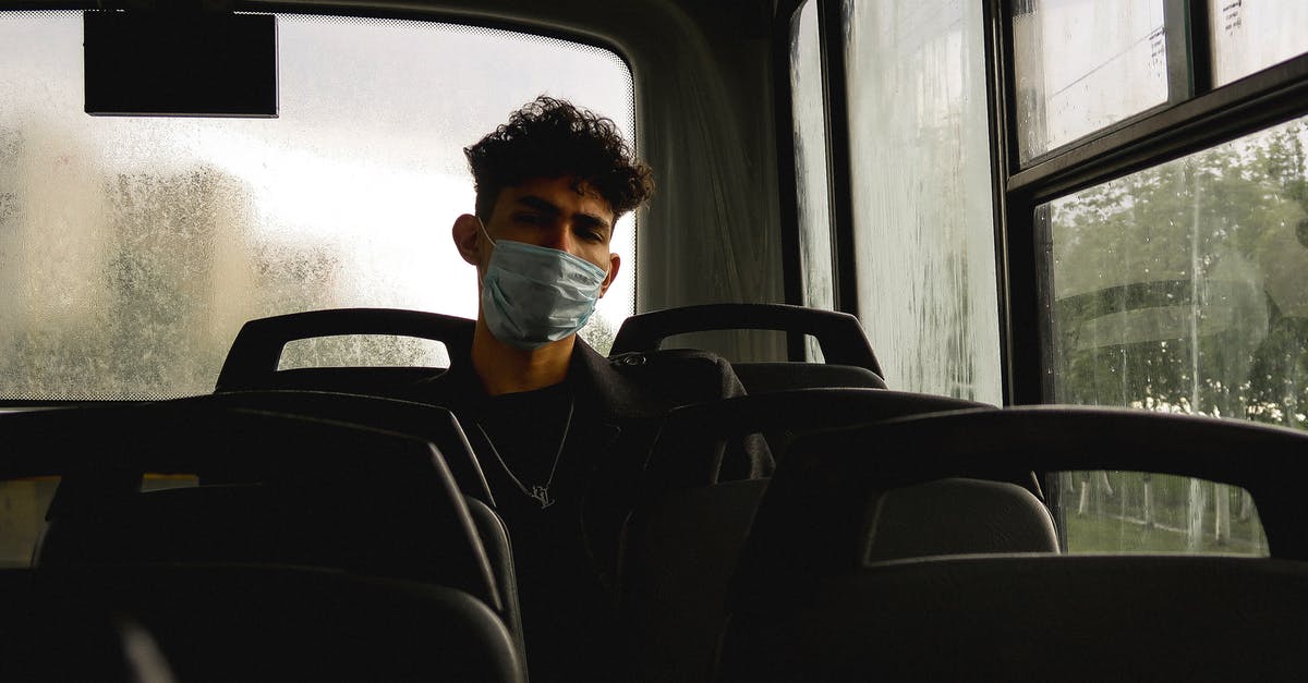 Best seats in a bus if travelling with kids [closed] - Calm young stylish male wearing medical mask sitting in bus in rainy weather