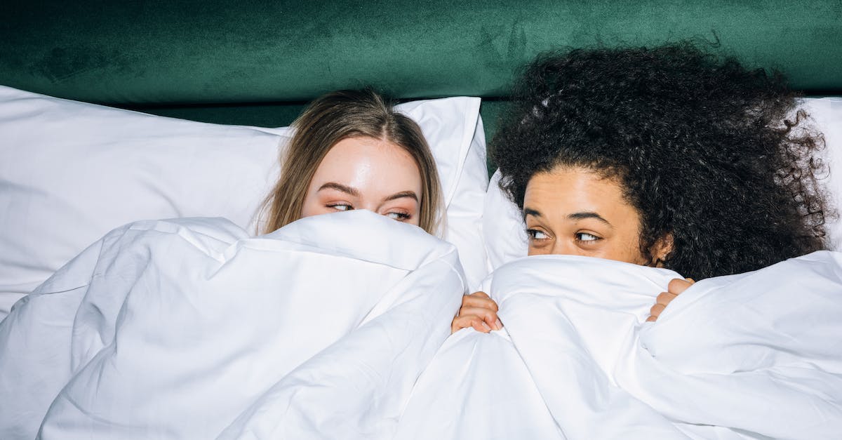 Best time for Mediterranean cruise - Two Young Women Lying on White Bed While Looking at Each Other