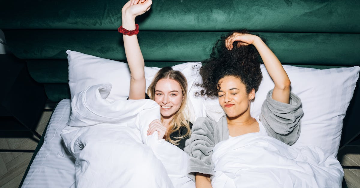 Best Time for Visiting the Curonian Spit - Two Young Women Lying on White Bed