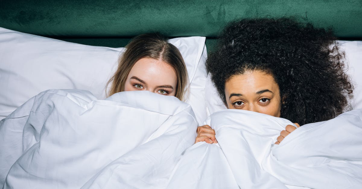 Best Time for Visiting the Curonian Spit - Two Young Women Lying on White Bed