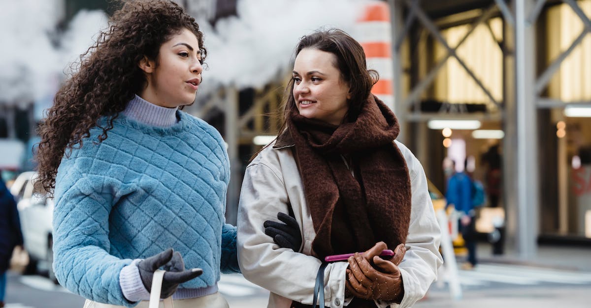 Best way to make my ears pop? - Positive stylish multiethnic women talking and crossing road in city