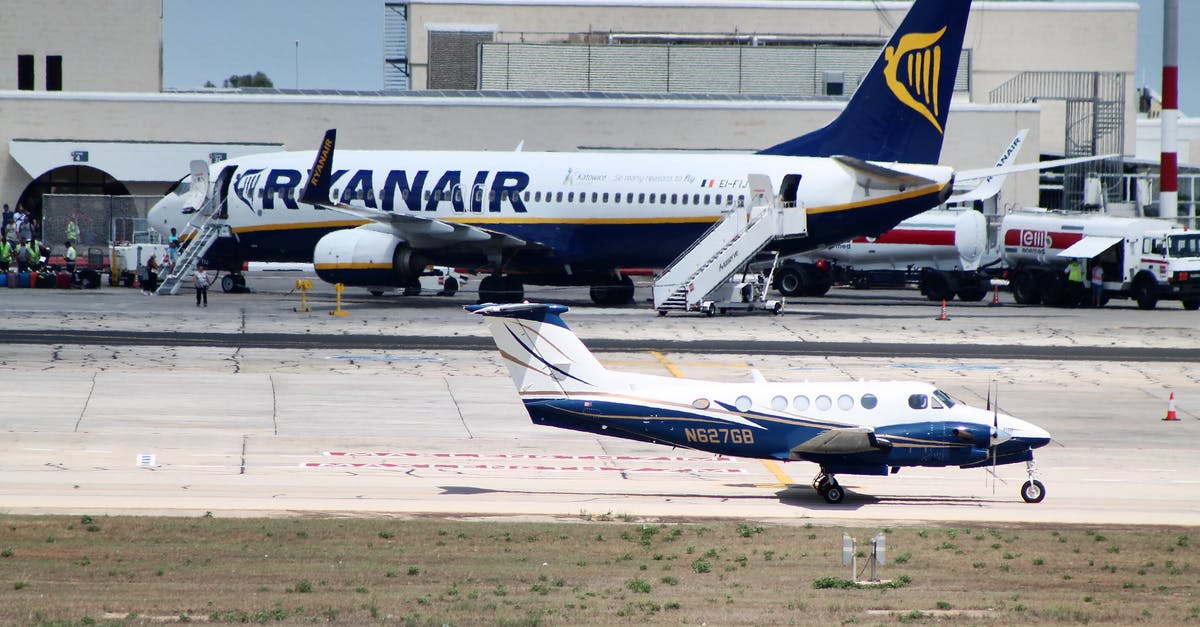 Best way to pay for airline tickets? - Civil utility and narrow body aircraft parked on runway tracks near modern airport building against cloudless blue sky