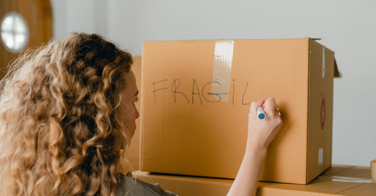 Best way to send valuable item back home while travelling (Istanbul)? - Back view of unrecognizable curvy female in casual clothes writing fragile on empty side of carton box while waiting for courier
