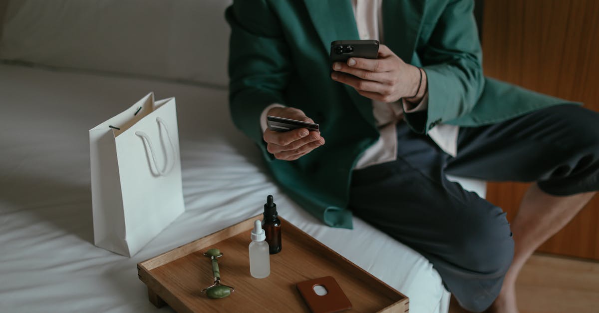 Best way to transfer Indian rupees to Bank of America? - Anonymous man using smartphone while placing order with credit card sitting near cosmetic products