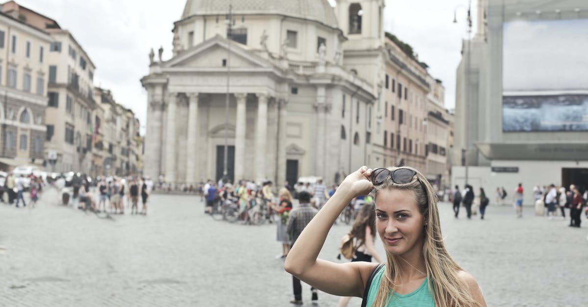 Bhutan Tourism - Medieval Places to visit in Bhutan [closed] - Stylish young female tourist in casual wear with sunglasses smiling and looking at camera while standing on old square Piazza del Popolo during summer holidays in Rome