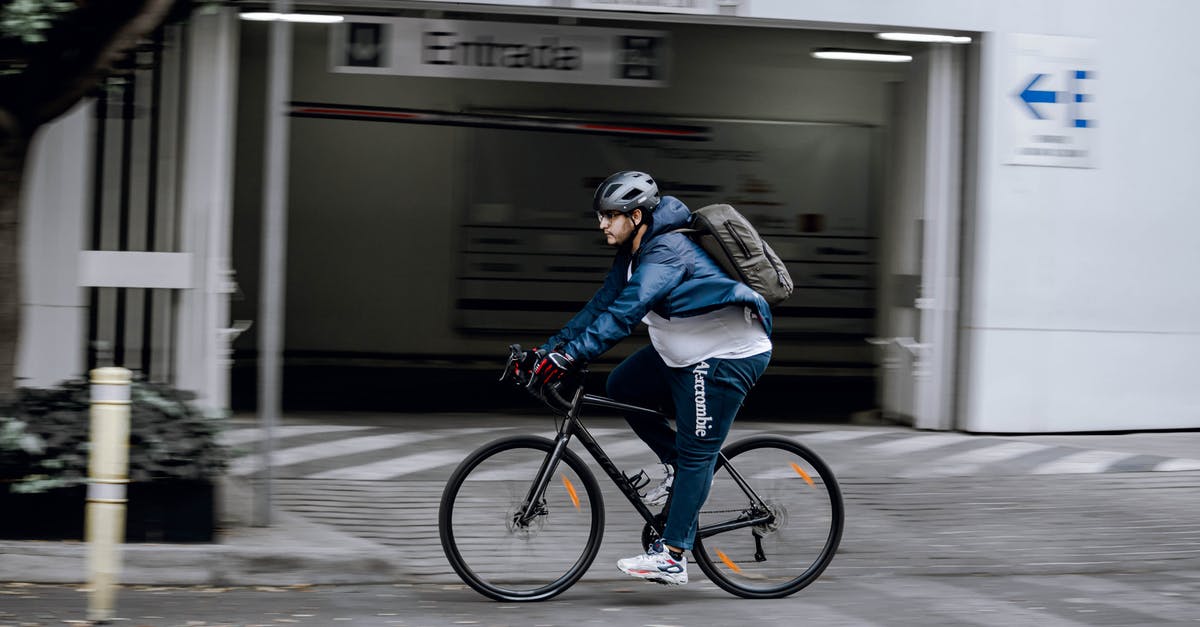 Bicycle helmet and backpack as carry-on in the US? - Man in Blue Jacket Riding on Black Bicycle