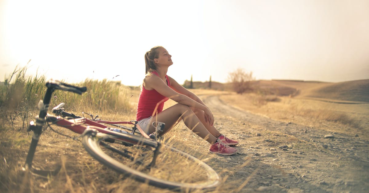 Bicycle rental in Belo Horizonte? - Full body of female in shorts and top sitting on roadside in rural field with bicycle near and enjoying fresh air with eyes closed