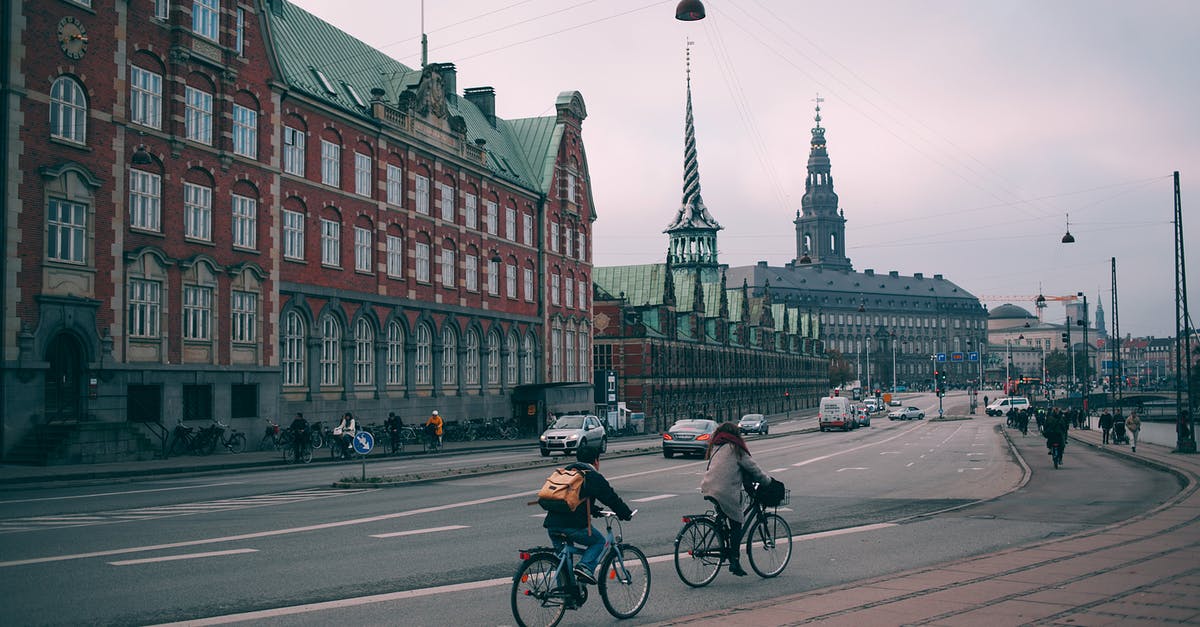 Bicycle routes in Europe - Cyclists riding along famous embankment in Copenhagen with historic Christiansborg palace and stock exchange building in Denmark on cloudy day