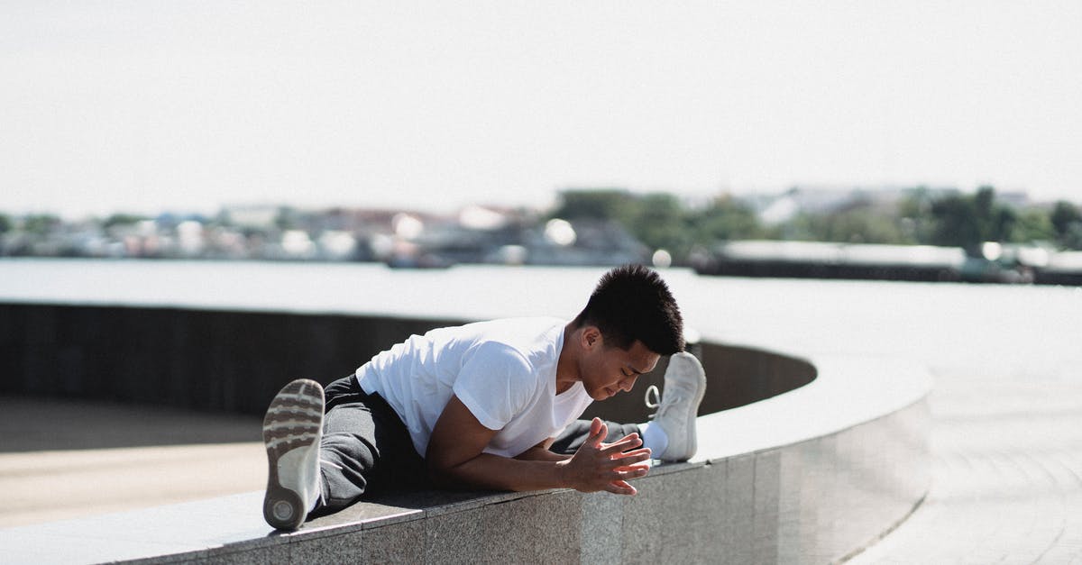 Big Bend border crossing -- safe for campers? - Full body sporty young Asian male in activewear doing split and bending body towards while warming up on embankment border on sunny weather