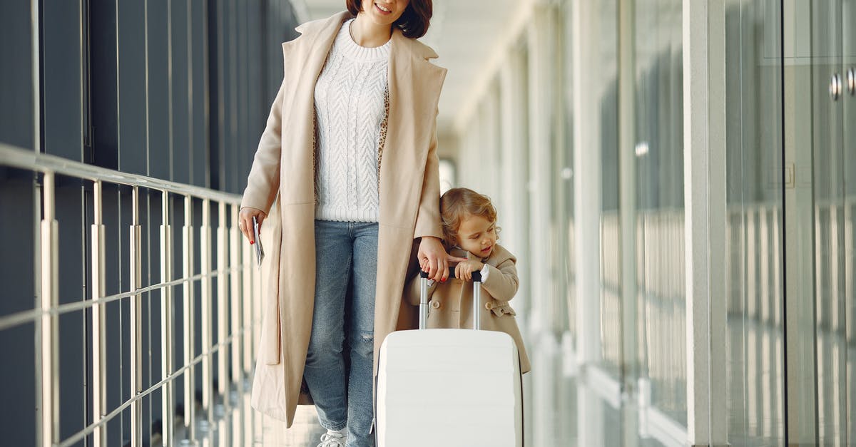 Bigger carry on baggage in Emirates - Positive mother and daughter with suitcase in airport corridor