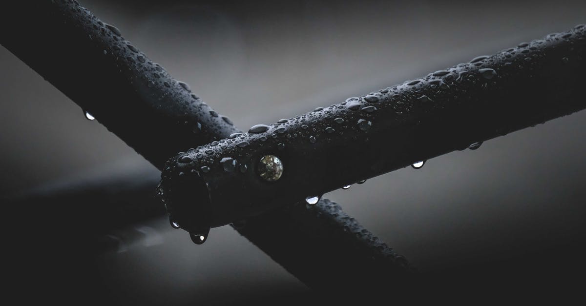 Black Labyrinth or Tube it in Waitomo? [closed] - Closeup of black metal pipes covered in water drops and attached with nail