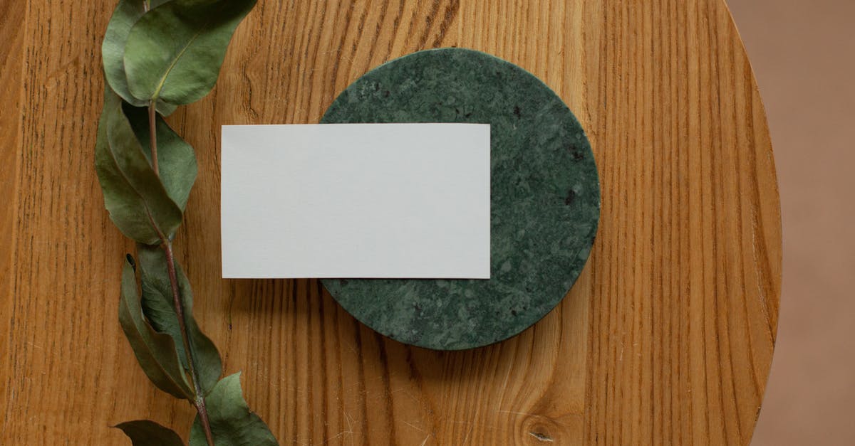 Blackberry Q10 SIM card in New Zealand - Top view of white mock up business card on round board placed on wooden table with green branch in room