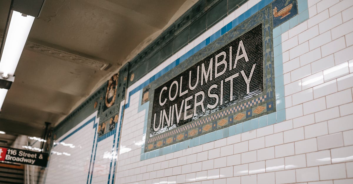 Board German train from next station - From below of wall with inscription with name of underground station made of tile and mosaic